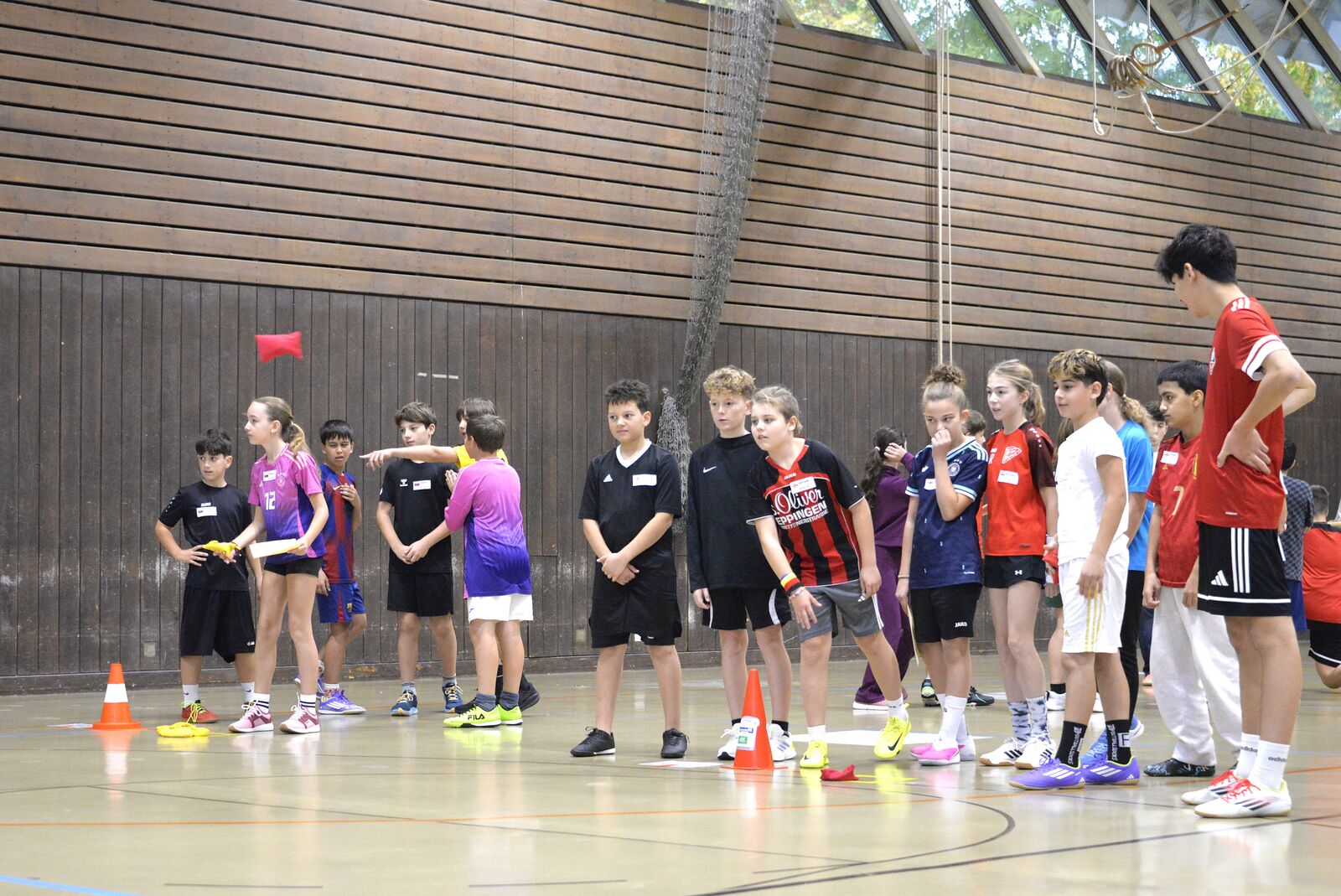 Eine Reihe Schülerinnen und Schüler in Sportkleidung steht in der Halle und wartet auf ihren Einsatz.